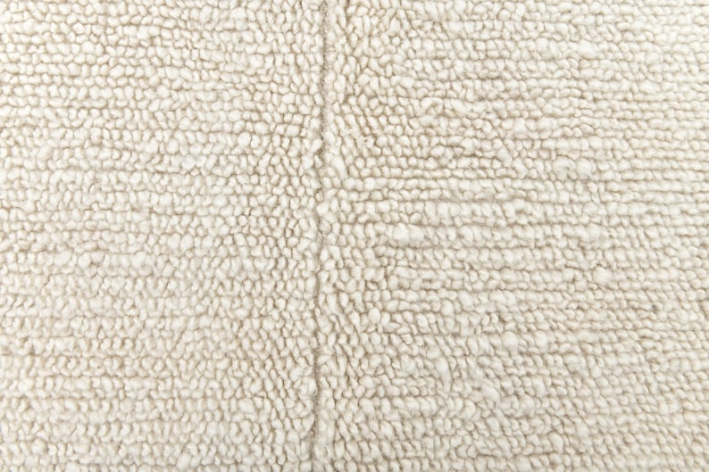 May include: Close-up of a white, fluffy, textured fabric. The fabric has a subtle, woven pattern.