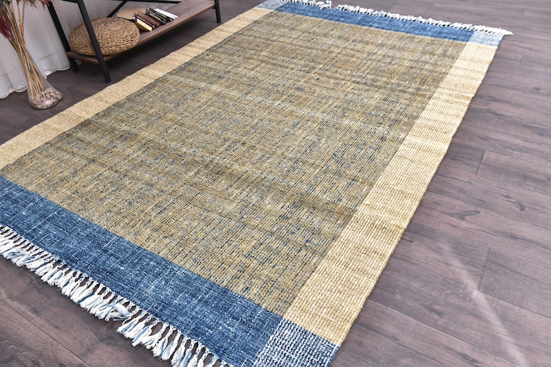 Handwoven area rug featuring geometric color blocks in rich navy blue, warm golden yellow, olive green and natural beige tones. This modern Turkish kilim style rug has a textured flat weave with white fringe edges, perfect for bohemian or Scandinavian interiors. Natural fiber construction creates an eco-friendly floor covering.