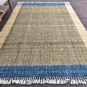 Handwoven area rug featuring geometric color blocks in rich navy blue, warm golden yellow, olive green and natural beige tones. This modern Turkish kilim style rug has a textured flat weave with white fringe edges, perfect for bohemian or Scandinavian interiors. Natural fiber construction creates an eco-friendly floor covering.