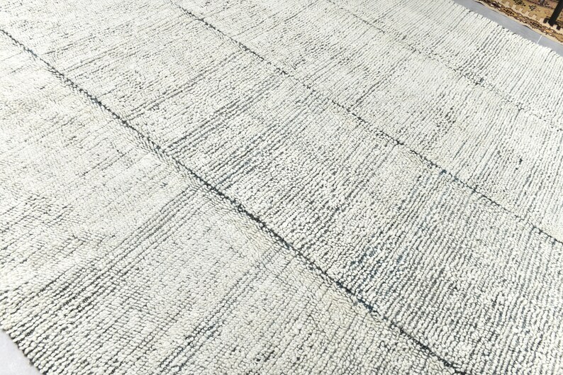 May include: A white and gray textured rug with a woven pattern. The rug has a subtle blue hue.