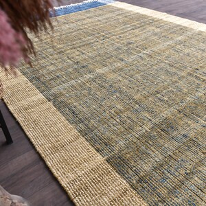 Handwoven area rug featuring geometric color blocks in rich navy blue, warm golden yellow, olive green and natural beige tones. This modern Turkish kilim style rug has a textured flat weave with white fringe edges, perfect for bohemian or Scandinavian interiors. Natural fiber construction creates an eco-friendly floor covering.