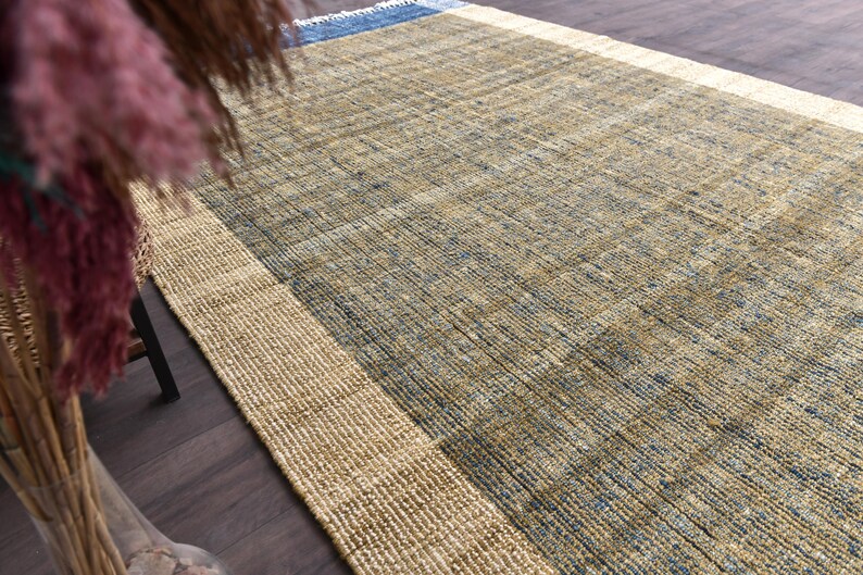 Handwoven area rug featuring geometric color blocks in rich navy blue, warm golden yellow, olive green and natural beige tones. This modern Turkish kilim style rug has a textured flat weave with white fringe edges, perfect for bohemian or Scandinavian interiors. Natural fiber construction creates an eco-friendly floor covering.