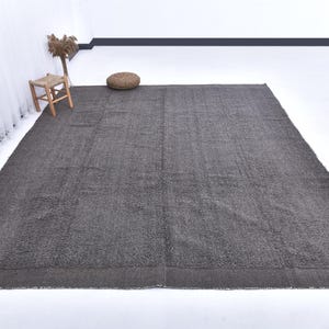 May include: A dark gray shag rug with a subtle texture. The rug is laid out on a white floor in a room with white walls.