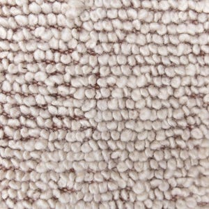 May include: Close-up of a beige textured fabric with a subtle brown woven pattern. The fabric has a soft, fuzzy texture.
