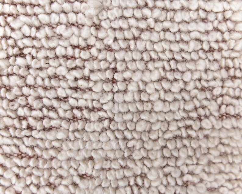 May include: Close-up of a beige textured fabric with a subtle brown woven pattern. The fabric has a soft, fuzzy texture.