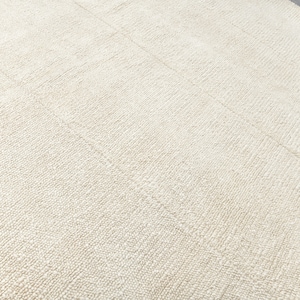 May include: A close-up of a white, textured rug with a subtle pattern. The rug is made of a soft, plush material and has a smooth, even surface.