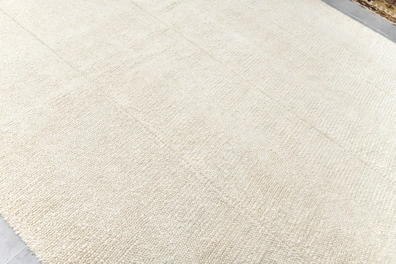 May include: A close-up of a white, textured rug with a subtle pattern. The rug is made of a soft, plush material and has a smooth, even surface.