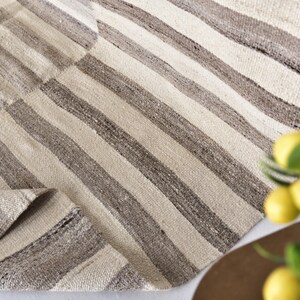 Pu&ograve; includere: Un tappeto tessuto a mano con un motivo a strisce in tonalit&agrave; beige e marrone. Il tappeto ha un aspetto e una sensazione naturali e rustici.
