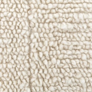 May include: Close-up of a cream-colored, fluffy, textured fabric. The fabric has a soft, fuzzy appearance.