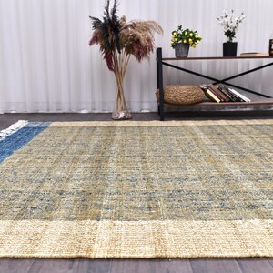 Handwoven area rug featuring geometric color blocks in rich navy blue, warm golden yellow, olive green and natural beige tones. This modern Turkish kilim style rug has a textured flat weave with white fringe edges, perfect for bohemian or Scandinavian interiors. Natural fiber construction creates an eco-friendly floor covering.