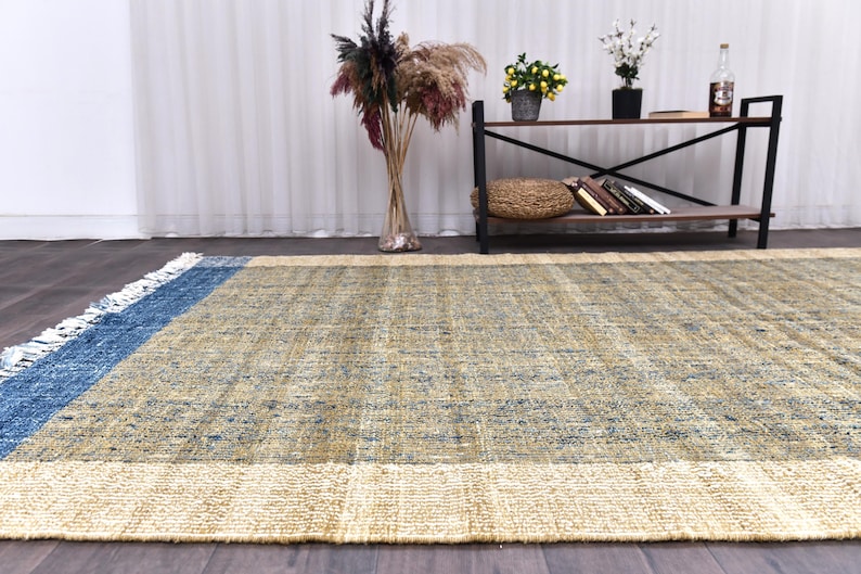 Handwoven area rug featuring geometric color blocks in rich navy blue, warm golden yellow, olive green and natural beige tones. This modern Turkish kilim style rug has a textured flat weave with white fringe edges, perfect for bohemian or Scandinavian interiors. Natural fiber construction creates an eco-friendly floor covering.