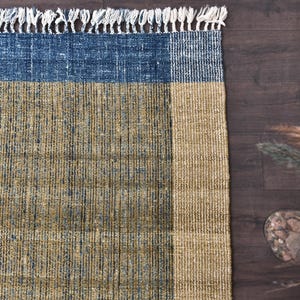 Handwoven area rug featuring geometric color blocks in rich navy blue, warm golden yellow, olive green and natural beige tones. This modern Turkish kilim style rug has a textured flat weave with white fringe edges, perfect for bohemian or Scandinavian interiors. Natural fiber construction creates an eco-friendly floor covering.