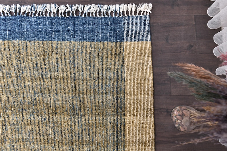 Handwoven area rug featuring geometric color blocks in rich navy blue, warm golden yellow, olive green and natural beige tones. This modern Turkish kilim style rug has a textured flat weave with white fringe edges, perfect for bohemian or Scandinavian interiors. Natural fiber construction creates an eco-friendly floor covering.