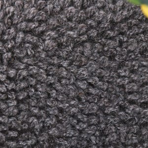 May include: Close-up of a dark gray fuzzy fabric texture. The fabric has a soft, plush feel and a slightly textured surface.