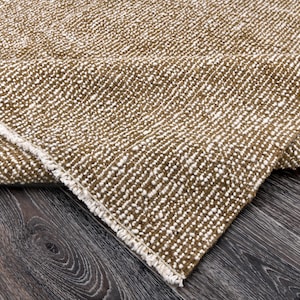 Puede incluir: Primer plano de una alfombra texturizada marrón y blanca con un borde de flecos. La alfombra está doblada por la mitad y la textura es visible.