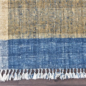Handwoven area rug featuring geometric color blocks in rich navy blue, warm golden yellow, olive green and natural beige tones. This modern Turkish kilim style rug has a textured flat weave with white fringe edges, perfect for bohemian or Scandinavian interiors. Natural fiber construction creates an eco-friendly floor covering.