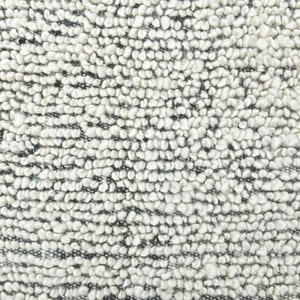 May include: Close-up of a white and gray textured fabric with a looped weave. The fabric has a soft, fuzzy appearance.