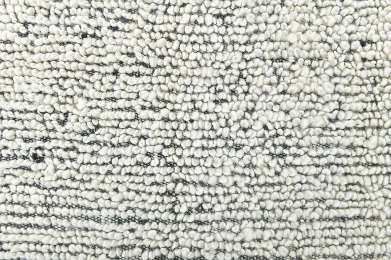 May include: Close-up of a white and gray textured fabric with a looped weave. The fabric has a soft, fuzzy appearance.