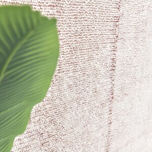May include: A close-up of a white and pink fluffy rug with a green leaf in the corner.