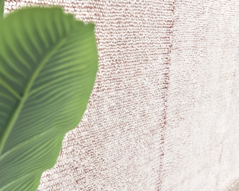 May include: A close-up of a white and pink fluffy rug with a green leaf in the corner.