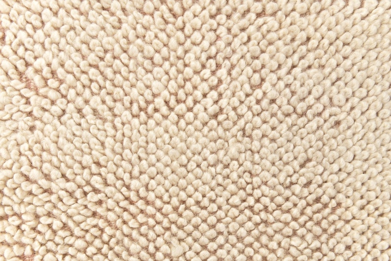 Puede incluir: Primer plano de una tela beige texturizada con un patr&oacute;n circular. La tela tiene una textura suave y peluda.