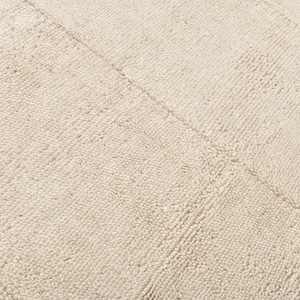May include: Close-up of a cream-coloured rug with a textured surface. The rug has a subtle pattern of raised lines that create a grid-like design.