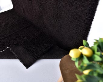 May include: Close-up of a black, textured rug with a soft, fuzzy surface. The rug is folded in half and the edge is visible.