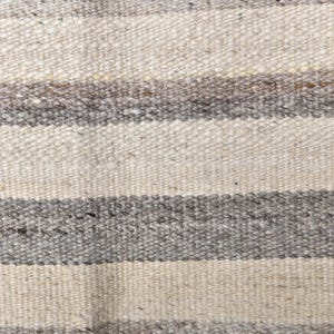 Pu&ograve; includere: Primo piano di un tappeto tessuto con strisce orizzontali in tonalit&agrave; di bianco e grigio.