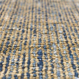 Handwoven area rug featuring geometric color blocks in rich navy blue, warm golden yellow, olive green and natural beige tones. This modern Turkish kilim style rug has a textured flat weave with white fringe edges, perfect for bohemian or Scandinavian interiors. Natural fiber construction creates an eco-friendly floor covering.