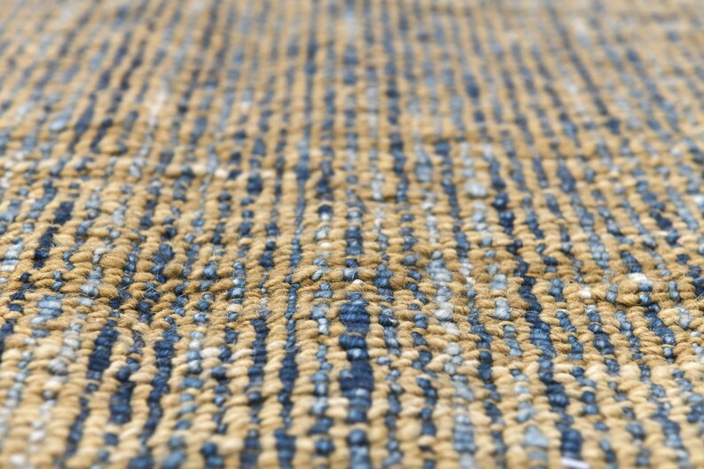 Handwoven area rug featuring geometric color blocks in rich navy blue, warm golden yellow, olive green and natural beige tones. This modern Turkish kilim style rug has a textured flat weave with white fringe edges, perfect for bohemian or Scandinavian interiors. Natural fiber construction creates an eco-friendly floor covering.