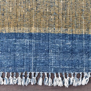 Handwoven area rug featuring geometric color blocks in rich navy blue, warm golden yellow, olive green and natural beige tones. This modern Turkish kilim style rug has a textured flat weave with white fringe edges, perfect for bohemian or Scandinavian interiors. Natural fiber construction creates an eco-friendly floor covering.