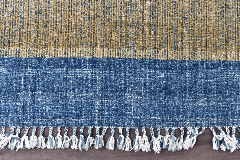 Handwoven area rug featuring geometric color blocks in rich navy blue, warm golden yellow, olive green and natural beige tones. This modern Turkish kilim style rug has a textured flat weave with white fringe edges, perfect for bohemian or Scandinavian interiors. Natural fiber construction creates an eco-friendly floor covering.