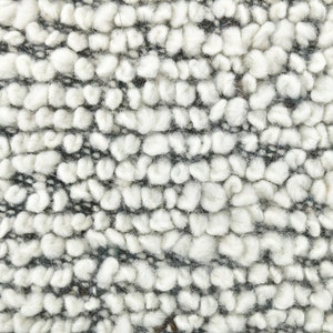 May include: Close-up of a white and gray textured fabric with a fuzzy, looped texture.