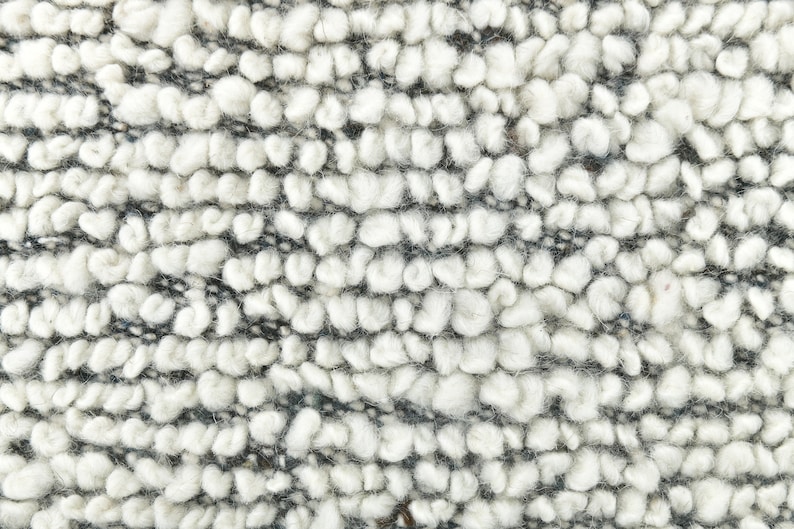 May include: Close-up of a white and gray textured fabric with a fuzzy, looped texture.