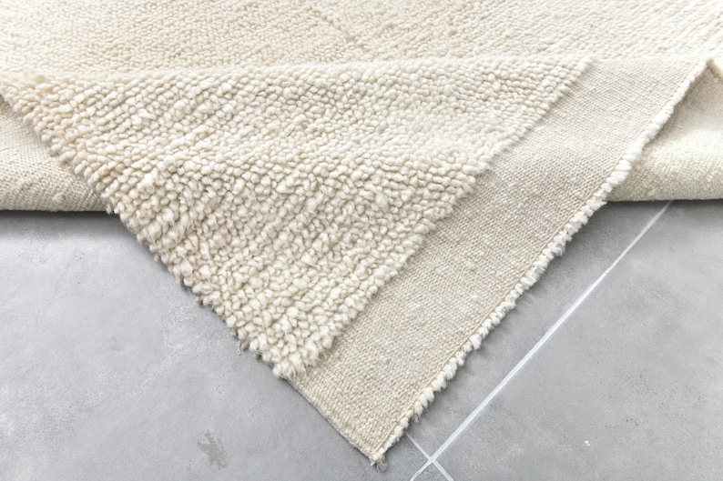 May include: A white, fluffy rug with a textured surface. The rug is folded in half, revealing a plain white underside.