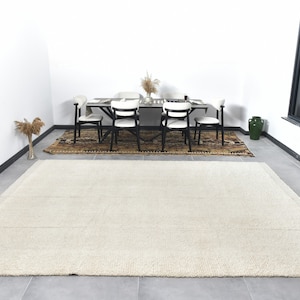 May include: A white shag rug with a subtle texture, placed in a room with a dining table and chairs. The rug is approximately 8 feet long and 6 feet wide.