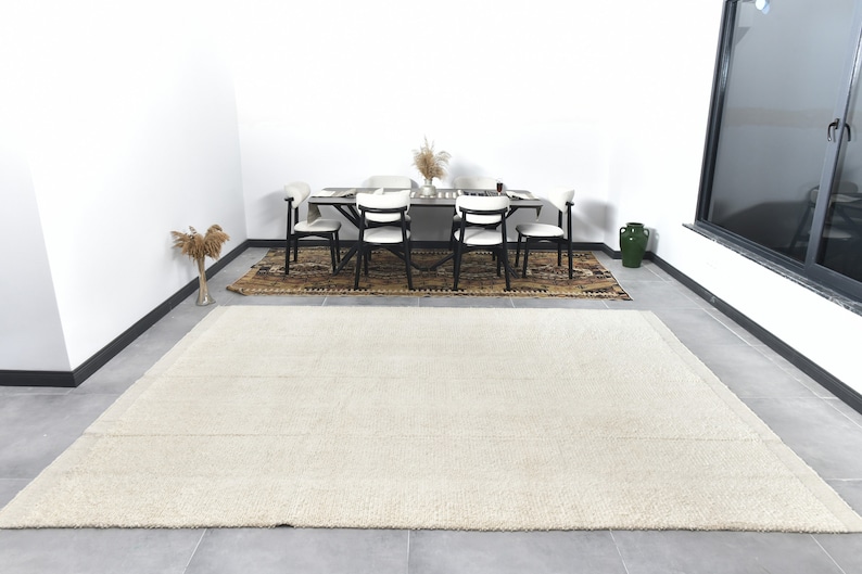 May include: A white shag rug with a subtle texture, placed in a room with a dining table and chairs. The rug is approximately 8 feet long and 6 feet wide.