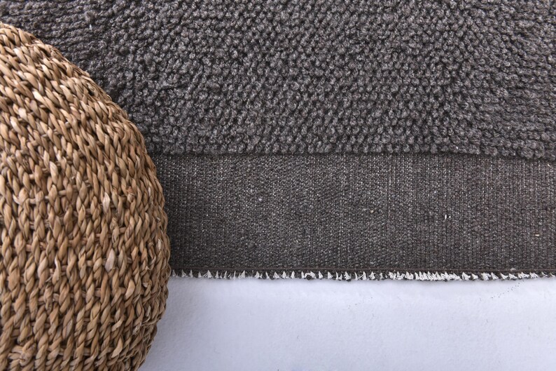 May include: A close-up of a brown woven basket with a gray and white textured rug underneath.