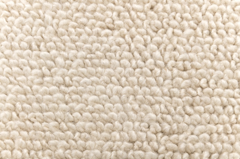 May include: Close-up of a cream-coloured, textured rug with a soft, fluffy surface.