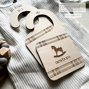 May include: Wooden baby clothes dividers with a plaid design and a rocking horse silhouette. One divider is labelled "0-3" and the other "nb" for newborn. The "newborn" divider has the word "newborn" below the rocking horse.