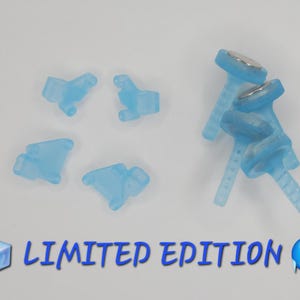 May include: A collection of light blue translucent plastic accessories, including four small shaped pieces and three T-shaped components with metallic circular tops. The text LIMITED EDITION is printed in blue at the bottom with ice cube and face emojis.