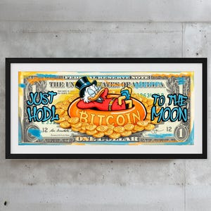 May include: Framed artwork depicting a one-dollar bill with a cartoon duck relaxing in a Bitcoin-themed pool of coins. The artwork includes the words "JUST HODL TO THE MOON" in graffiti-style lettering, adding a modern touch.