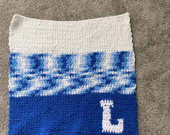 May include: A blue and white crocheted baby blanket with the letter "L" in white yarn.