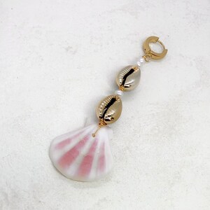 May include: Gold hoop earring with a pink seashell charm and two gold cowrie shells with white pearl beads.