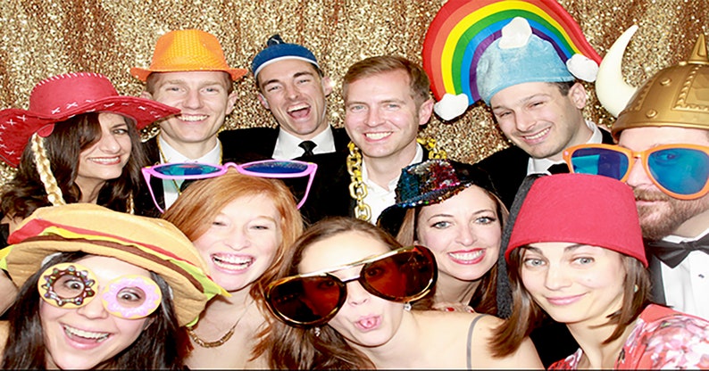 Puede incluir: Un grupo de amigos posan para una foto de cabina fotogr&aacute;fica con varios sombreros y accesorios. Los sombreros incluyen un sombrero de vaquero, un casco vikingo, un sombrero arco&iacute;ris, un fedora y una boina. Los accesorios incluyen gafas de sol, un bigote falso y una barba falsa.