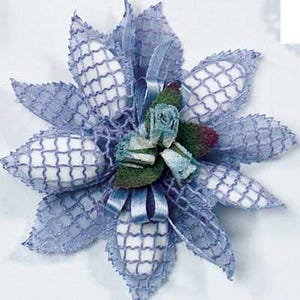 May include: A blue and white favor box with a white tulle bow and a small blue flower arrangement. The favor box is made of a delicate, lacy material.