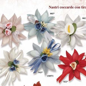 May include: Assortment of six different fabric flower arrangements with ribbon and a small decorative element in the center. The flowers are in shades of pink, white, blue, and red. The flowers are labeled with numbers 001, 002, 003, 005, 022, and 043.