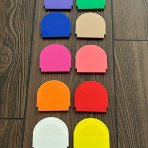 Puede incluir: Diez piezas de plástico en forma de semidomo en varios colores, incluyendo morado, verde, azul, beige, rosa, naranja, rojo, blanco y amarillo.