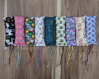 May include: Ten colorful catnip kick toys with different patterns. The toys are made of fabric and have a long string attached to each one. The patterns include a cat, a llama, a floral design, a cartoon character, and a  "MEOW" design.