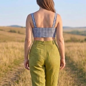 May include: A cropped top featuring a black and white gingham check pattern with wide shoulder straps, paired with high-waisted olive green trousers that have a structured waistband, belt loops, and two visible back pockets.